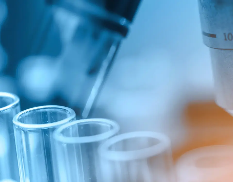 Pipette und Reagenzgläser vor einem Mikroskop