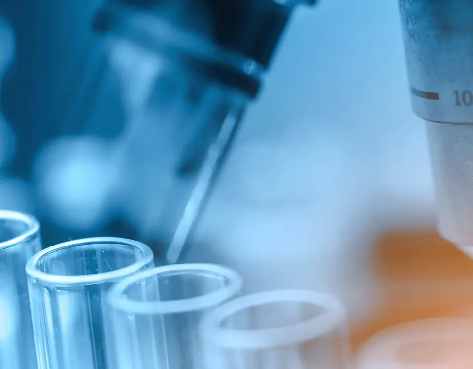 Pipette und Reagenzgläser vor einem Mikroskop