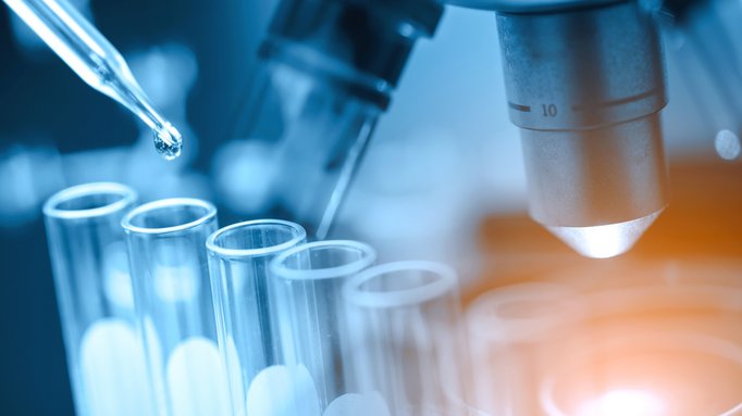Pipette und Reagenzgläser vor einem Mikroskop