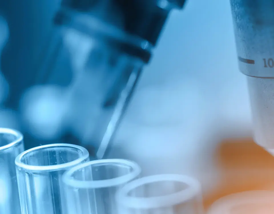 Pipette und Reagenzgläser vor einem Mikroskop