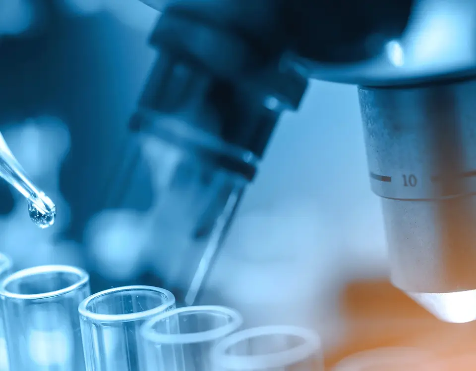 Pipette und Reagenzgläser vor einem Mikroskop