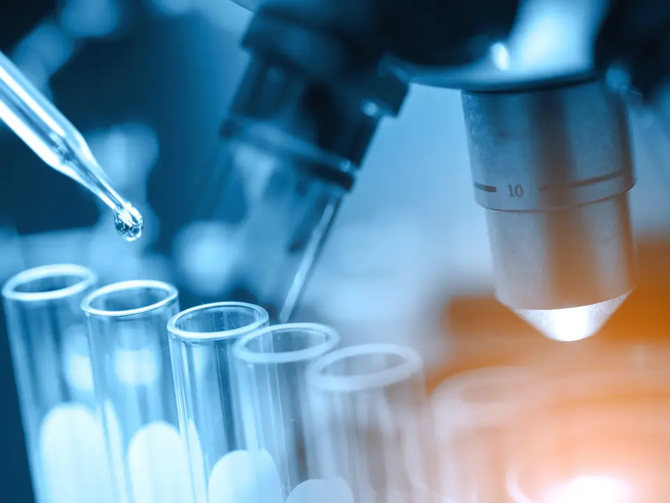 Pipette und Reagenzgläser vor einem Mikroskop