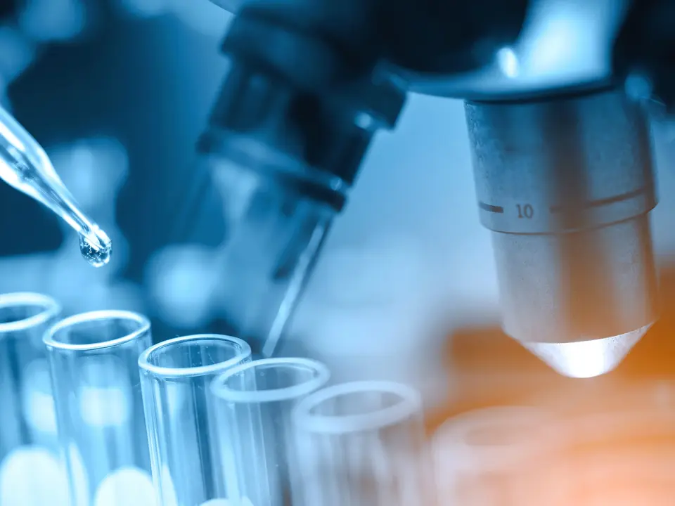 Pipette und Reagenzgläser vor einem Mikroskop